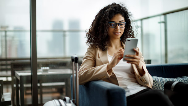 Women with suitcase sits and looks at her phone
